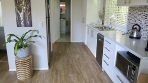 Una cocina moderna con armarios blancos, un refrigerador de acero inoxidable, un lavavajillas y una tetera sobre la encimera.