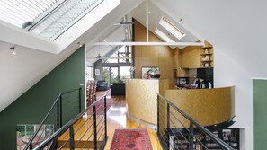 Un interior espacioso con techo alto, una escalera, una zona de cocina y vistas al exterior.