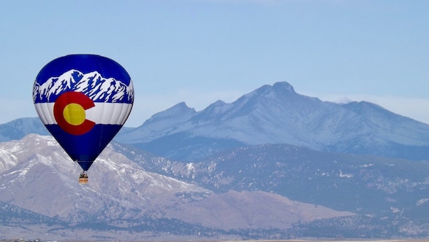 A hot air balloon with a mountain and flag design, flying over a mountainous landscape. - Cozy House With Hot Tub and Gaming Room (Colorado Springs)