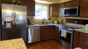 A modern kitchen with stainless steel appliances, granite countertops, and wooden cabinets. - Cozy House With Hot Tub and Gaming Room (Colorado Springs)