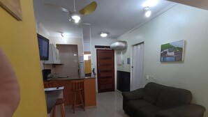 Ein modernes Wohnzimmer mit einer Couch, einem Essbereich mit Bar und einer Küche mit Fernseher.