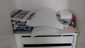 Ein Lagerraum mit gefalteter Kleidung und einem weißen Kopfkissen.