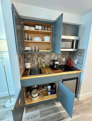 A compact kitchen with a built-in microwave, a sink, and a coffee maker.