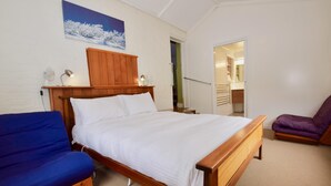 Un dormitorio con una cama de madera, un sofá azul y una silla morada.