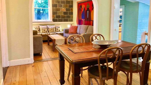 Un comedor con una mesa y sillas de madera, una pared de piedra y una ventana con vistas.