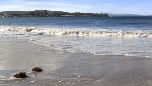 A beach with waves, a distant shoreline, and a clear sky. - summer beach house  (Southport)