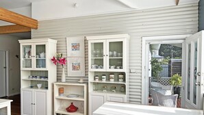 A kitchen with white cabinetry, open shelves, and a view to the outside.
