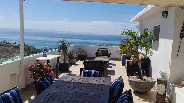 A balcony with a view of the ocean, outdoor furniture, and potted plants. - Spectacular Master Penthouse - Best Ocean view and sunsets on the Sea of Cortez (La Paz)