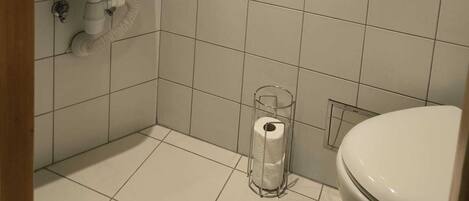 A small, clean bathroom with white tiles, a sink, and a toilet.