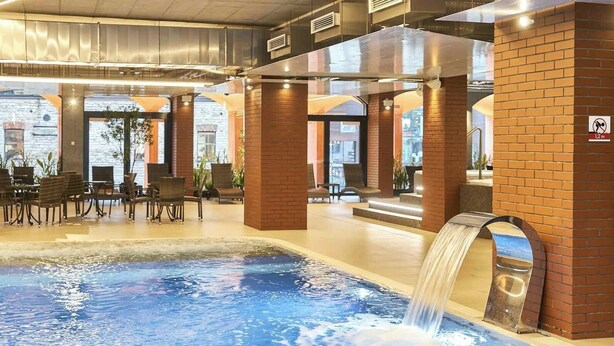 A hotel lobby with a pool, seating area, and brick walls. - Sunny Balcony Suite by Rotermann City Apts (Tallinn)