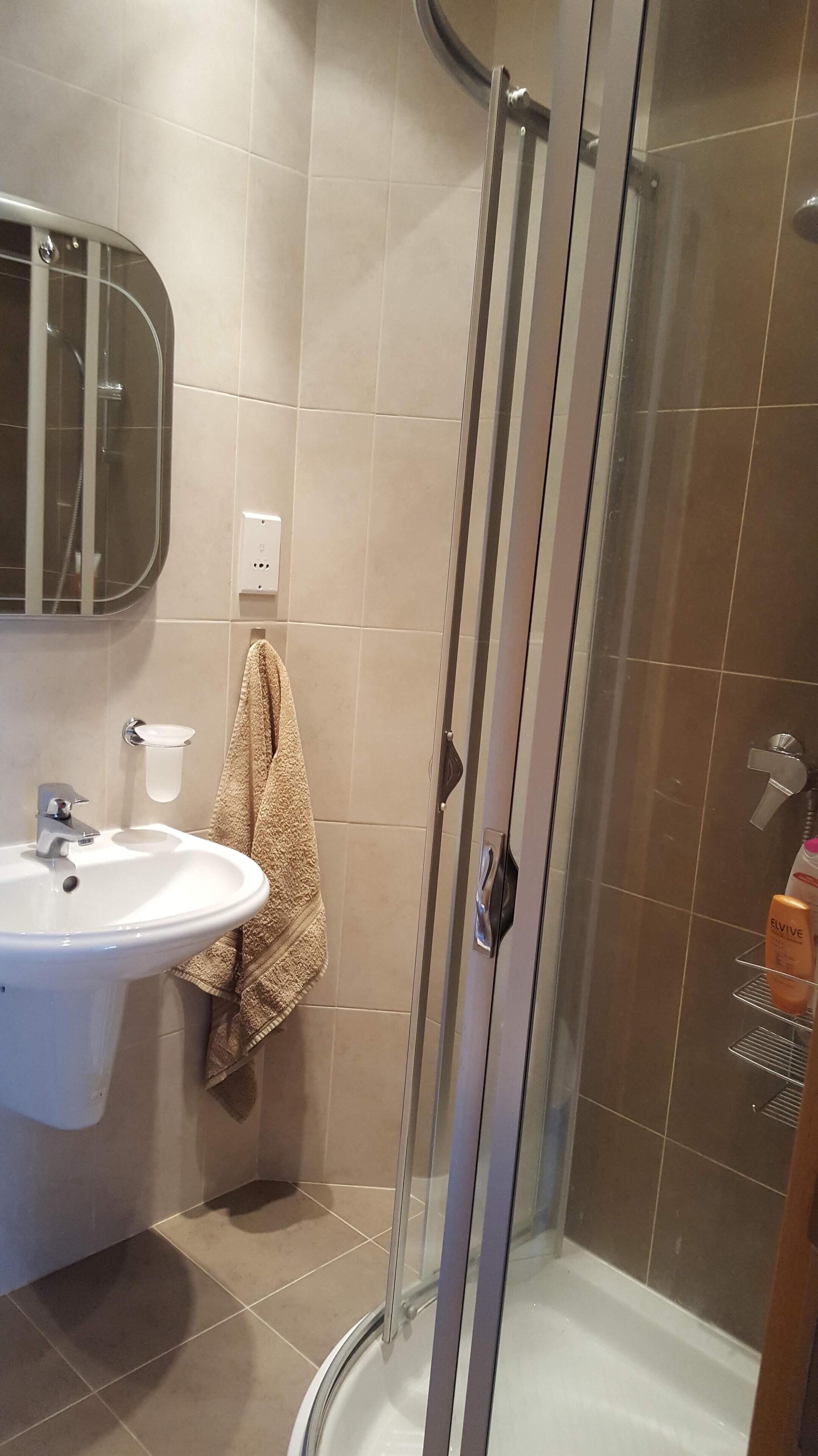 Un baño con ducha de vidrio, lavamanos y espejo.