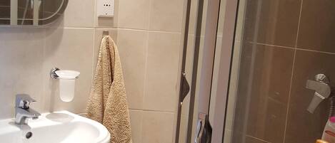 Un baño con ducha de vidrio, lavamanos y espejo.