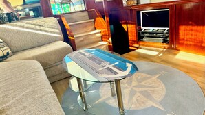 A round glass table with a compass design, a sofa, and a wooden cabinet with a television.