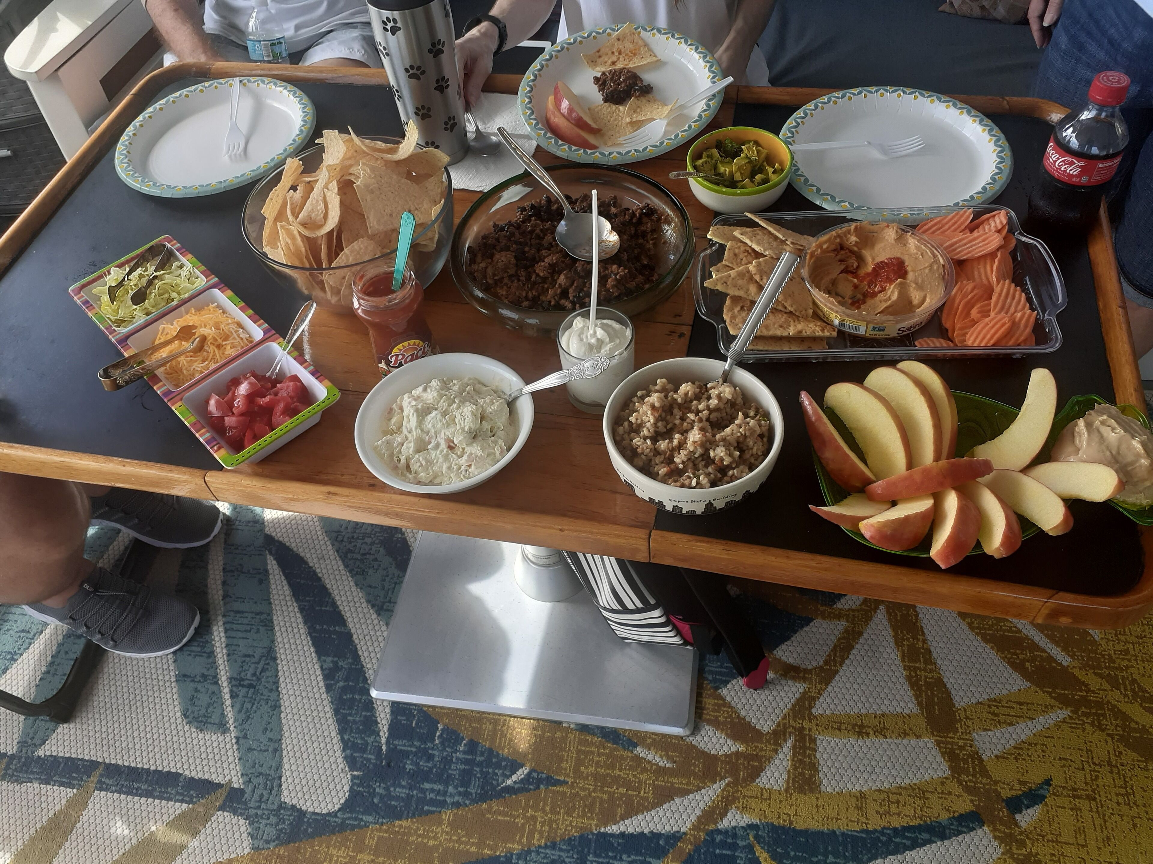 Ein Tablett mit verschiedenen Speisen, darunter Chips, Dips und Obst.