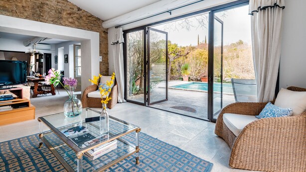 A spacious living room with a large sliding glass door leading to a pool area, a television, and a dining area.