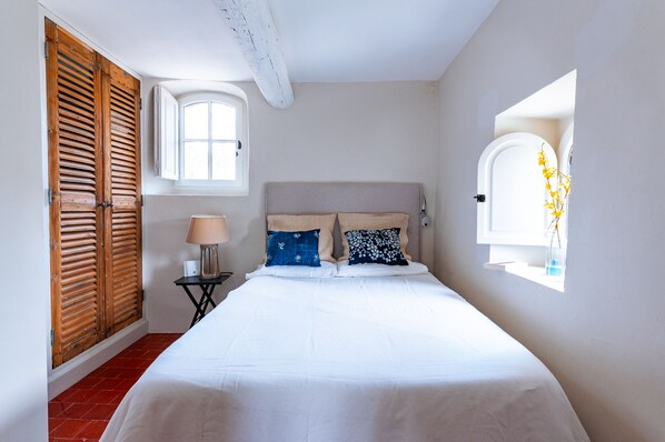 Un dormitorio con cama, ventana, lámpara y puerta de madera.