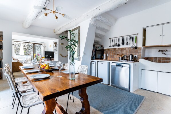 Una cocina moderna con armarios blancos, una mesa de comedor de madera y un ventanal grande.