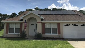 A single-story house with a beige facade, a red brick chimney, and a garage. - Premier Host Rated Villa - Private solar heated pool & family games room   (Davenport)