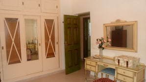 A room with a wardrobe, a mirror, and a dresser.