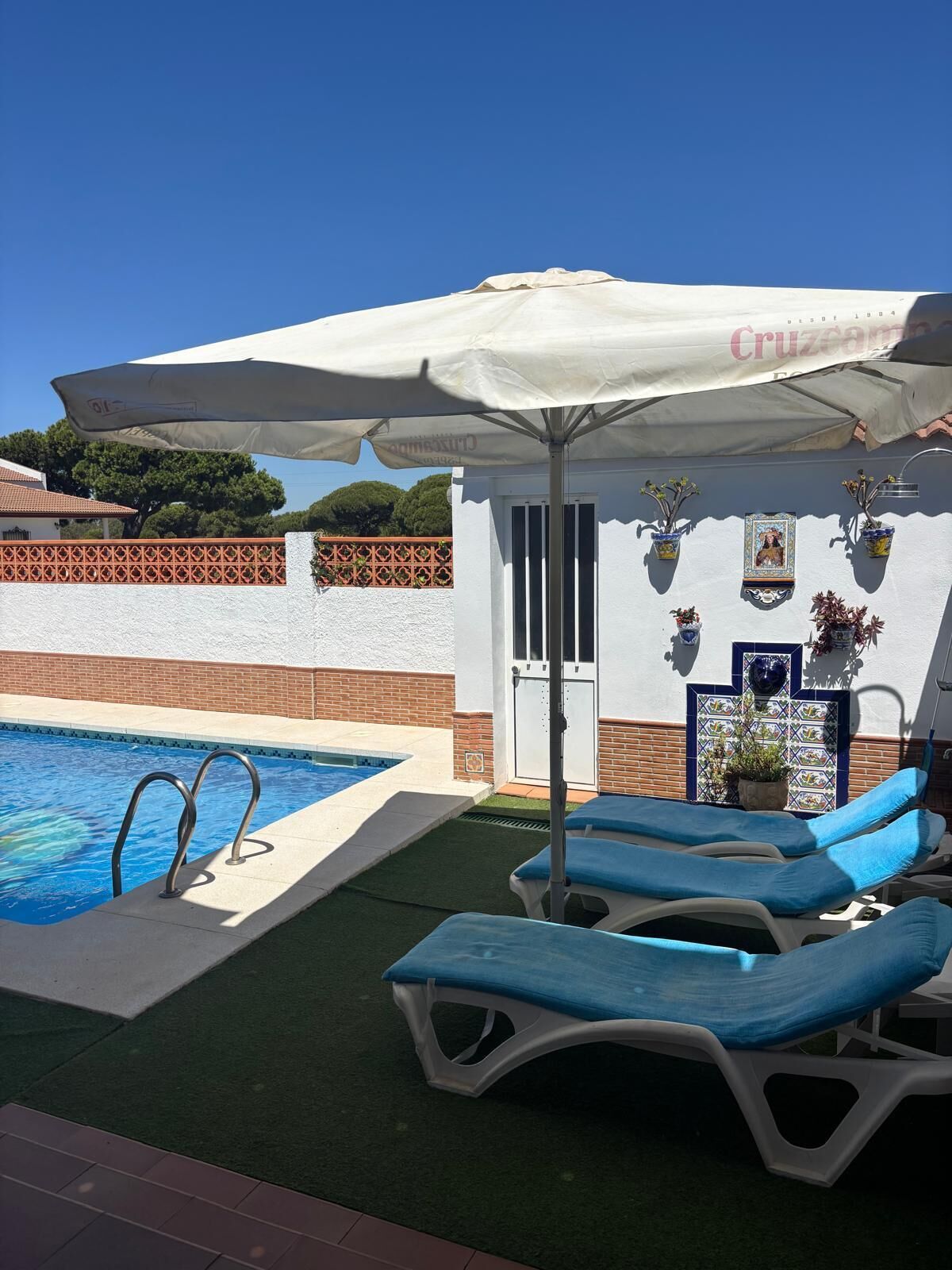 En swimmingpool med solstolar och ett parasoll.