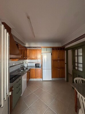 Eine Küche mit Holzausstattung, einem Kühlschrank, einer Mikrowelle und einem Spülbecken.