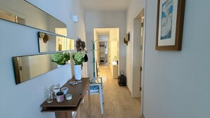 A hallway with a wooden table, a mirror, and a framed picture on the wall. - The Moll Apartment - Seaside Holiday Home (Il-Mellieha)