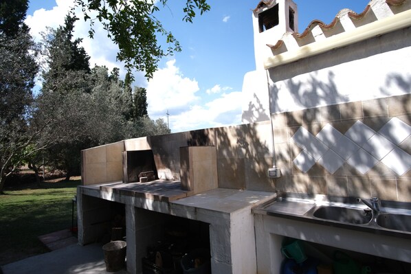An outdoor kitchen area with a stone countertop, a sink, and a grill. - Villa Pepa S'abuleu, detached villa with garden and swimming pool. (Pula)