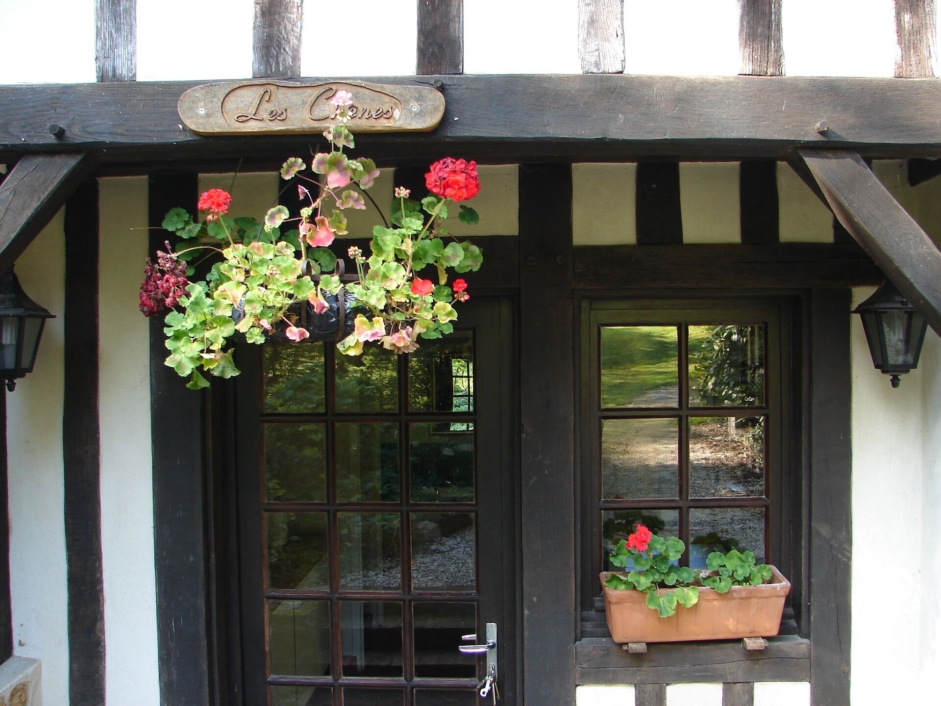 Un bâtiment traditionnel, orné d’une jardinière suspendue et d’un pot de fleurs posé sur le rebord de la fenêtre.
