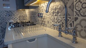 Una cocina con un lavaplatos de acero inoxidable, una estufa a gas y un salpicadero decorativo.