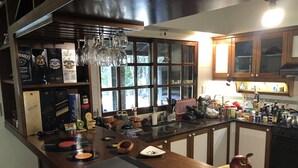 A kitchen with a wooden countertop, a laptop, a bowl of fruit, and various kitchen items. - Lo del Colo (Canning)