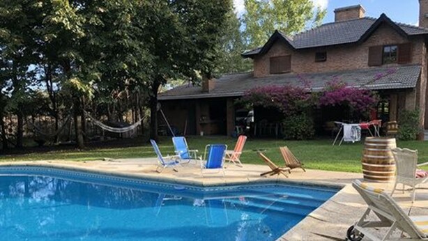 A swimming pool with lounge chairs and a house in the background. - Lo del Colo (Canning)