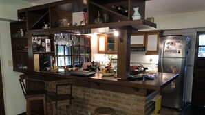 A kitchen with a brick island, wooden bar stools, and a stainless steel refrigerator. - Lo del Colo (Canning)
