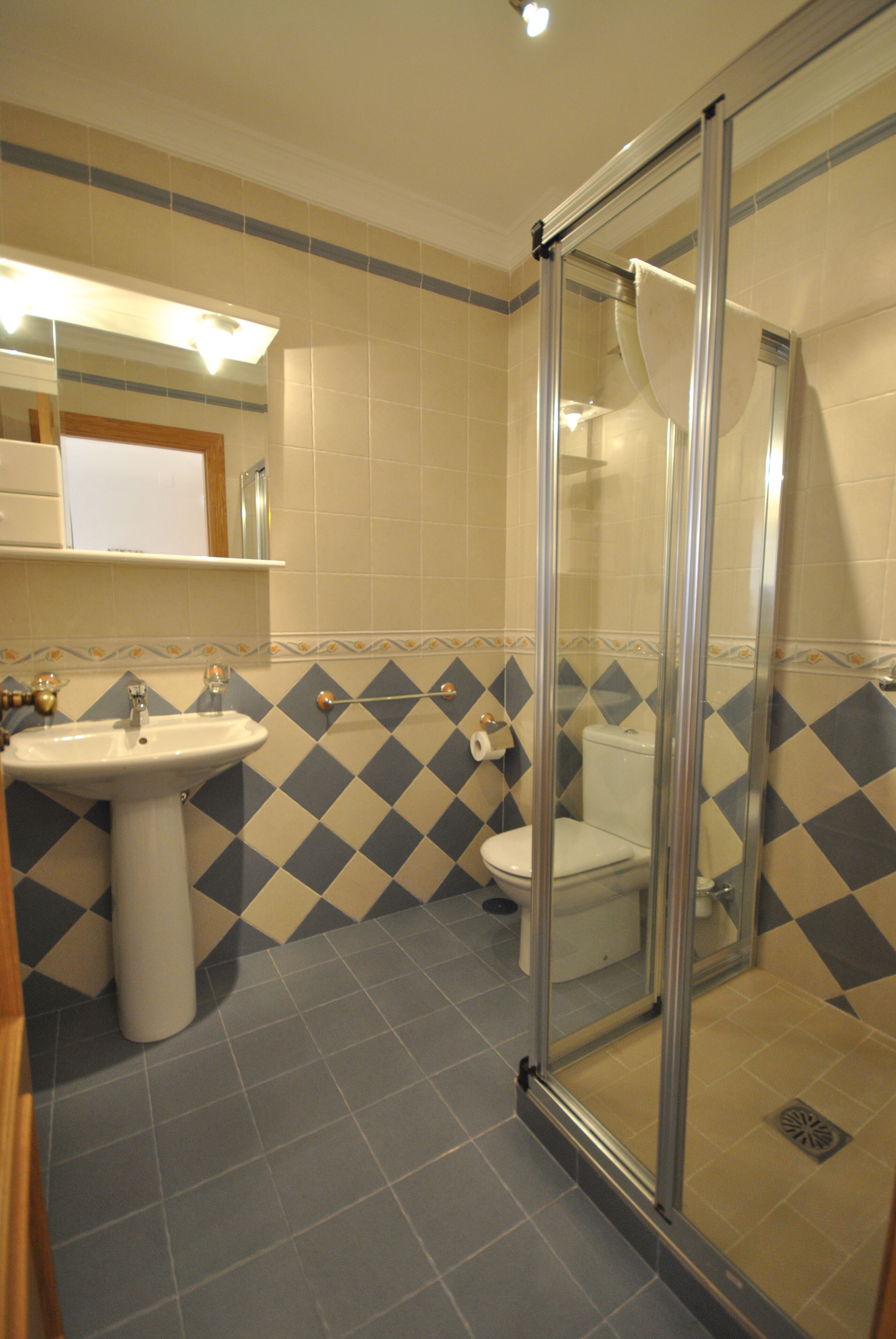 A bathroom with a glass-enclosed shower, a sink, and a toilet.