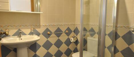 A bathroom with a glass-enclosed shower, a sink, and a toilet.