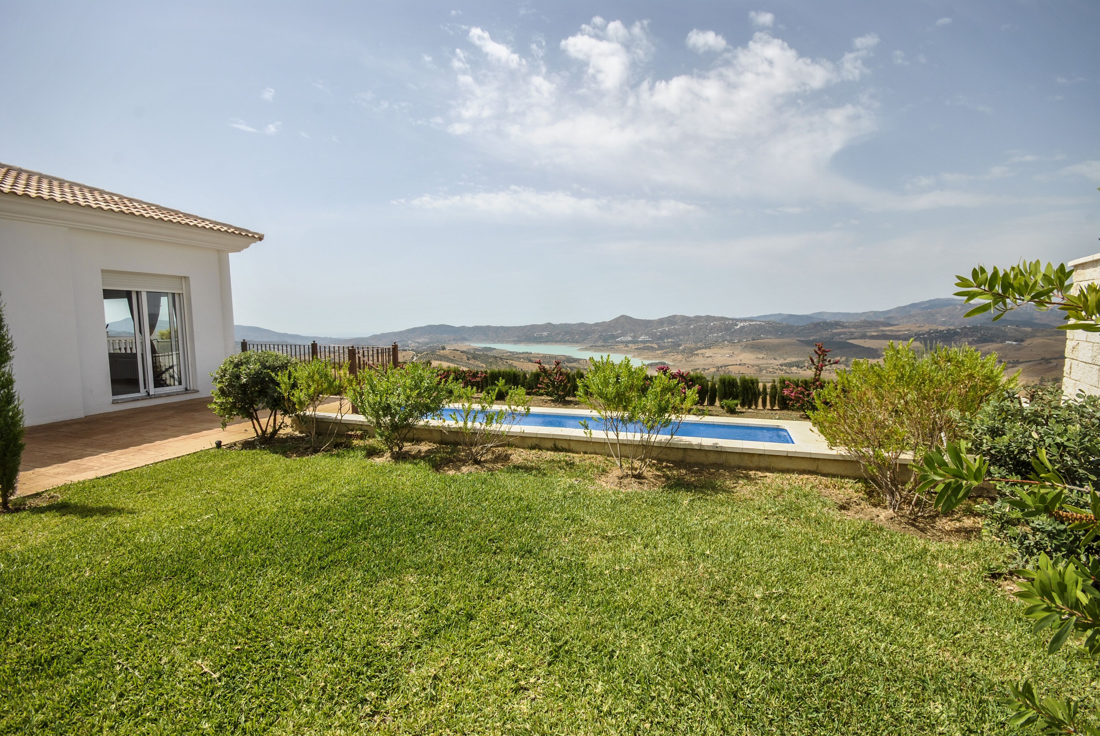 Ein Haus mit Schwimmbad, Rasen und Blick auf ferne Hügel.