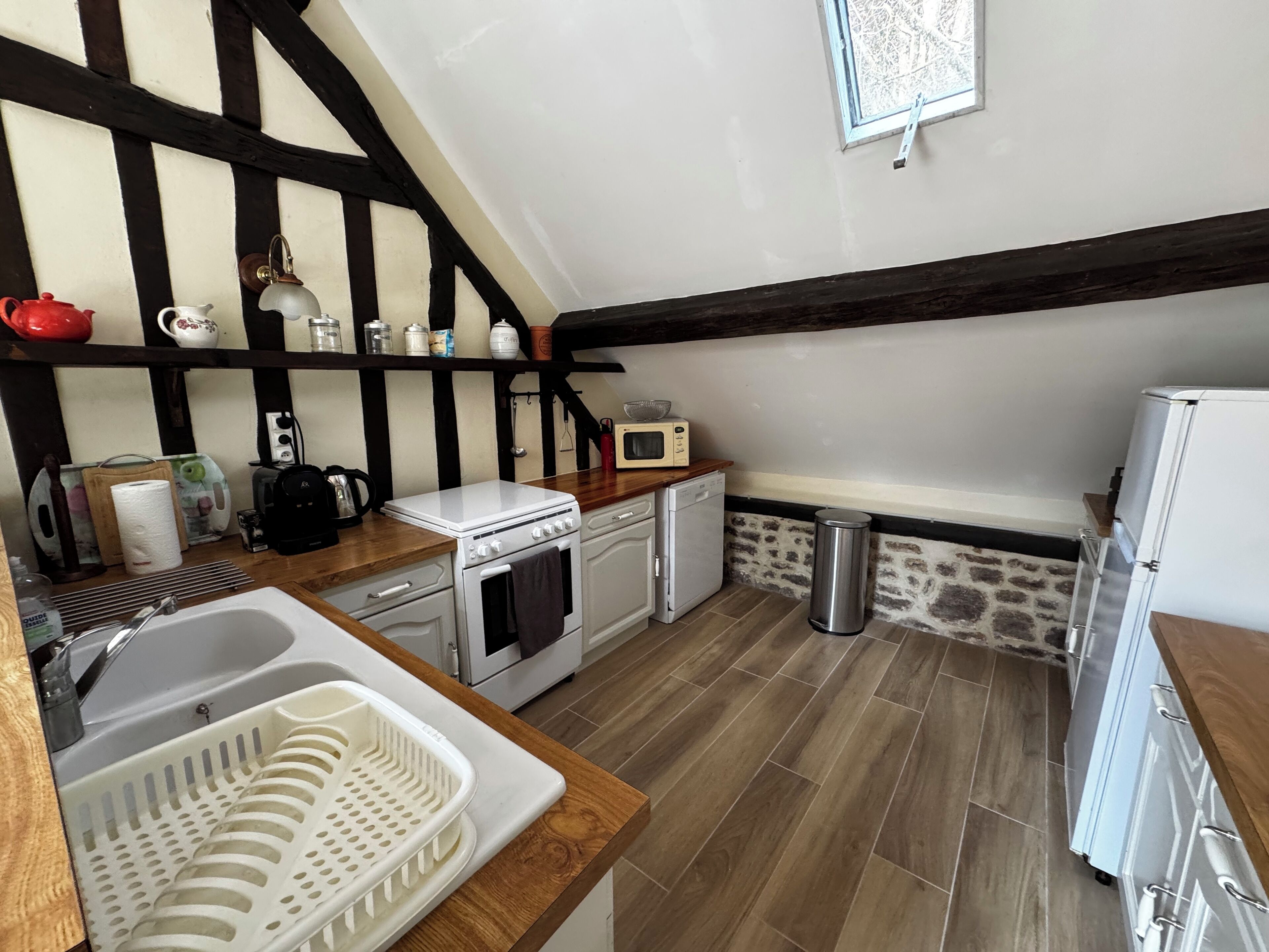 Una cocina compacta con encimera de madera, estufa blanca, microondas y refrigerador.