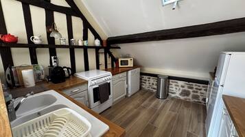 Una cocina compacta con encimera de madera, estufa blanca, microondas y refrigerador.