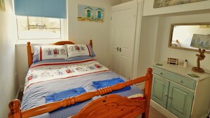 A bedroom with a wooden bed, a dresser, and a window with a blue blind. - Cultural Heart of Margate (Margate)
