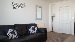 A room with a black leather sofa, a blue mirror, a white door, and a floor lamp. - Cultural Heart of Margate (Margate)