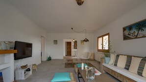 Ein modernes Wohnzimmer mit Fernseher, Sofa, Couchtisch und Essbereich.