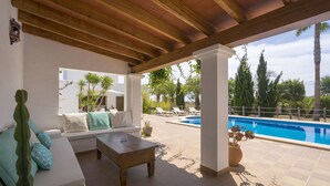 Eine Terrasse im Freien mit Pool, Holzboden und Sitzgruppe mit Kissen.