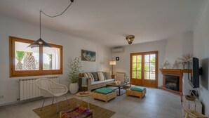 Ein Wohnzimmer mit einer Couch, Sesseln, einem Kamin und einem Fernseher.