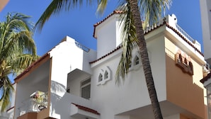 A multi-story residential building with balconies, a gated entrance, and a staircase leading to the upper floors. - Bungalow - Feet in the water (Flic En Flac)