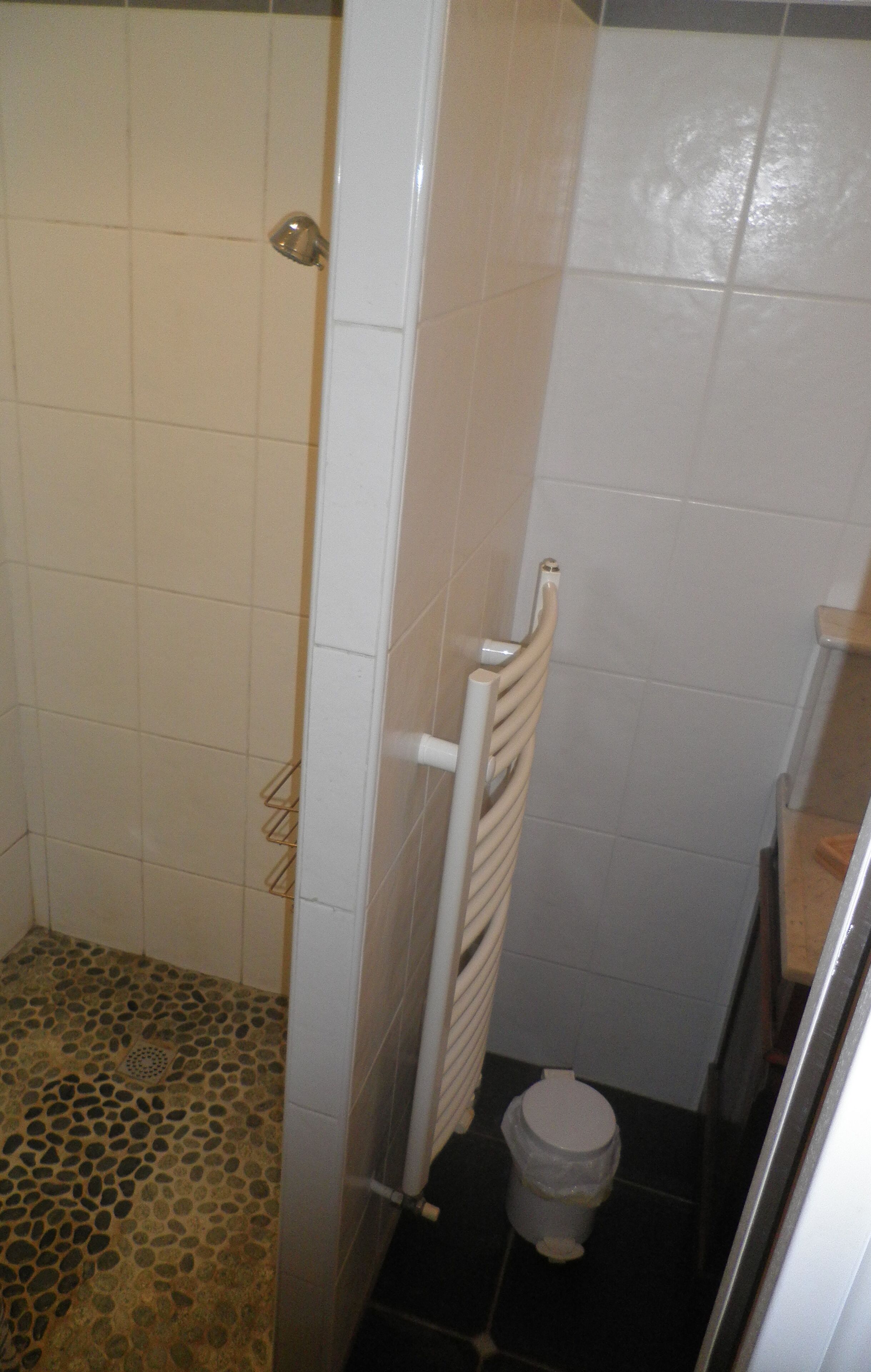 Kylpyhuone, jossa on suihku, laatoitetut seinät, wc ja roskakori.