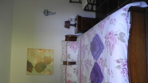 A bedroom with a bed, a nightstand, a lamp, a wall-mounted shelf, and a painting. - Au Bas Chalonge l'Appart (Ligné)