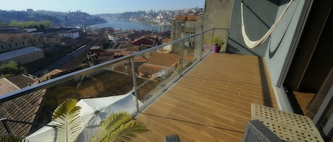 Un balcon offrant une vue sur le paysage urbain, avec des bâtiments et une étendue d’eau.