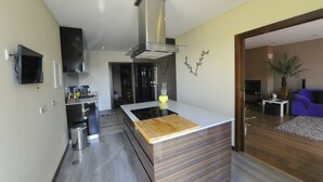 Een moderne keuken met een centraal eiland, roestvrijstalen apparatuur en een groot raam.