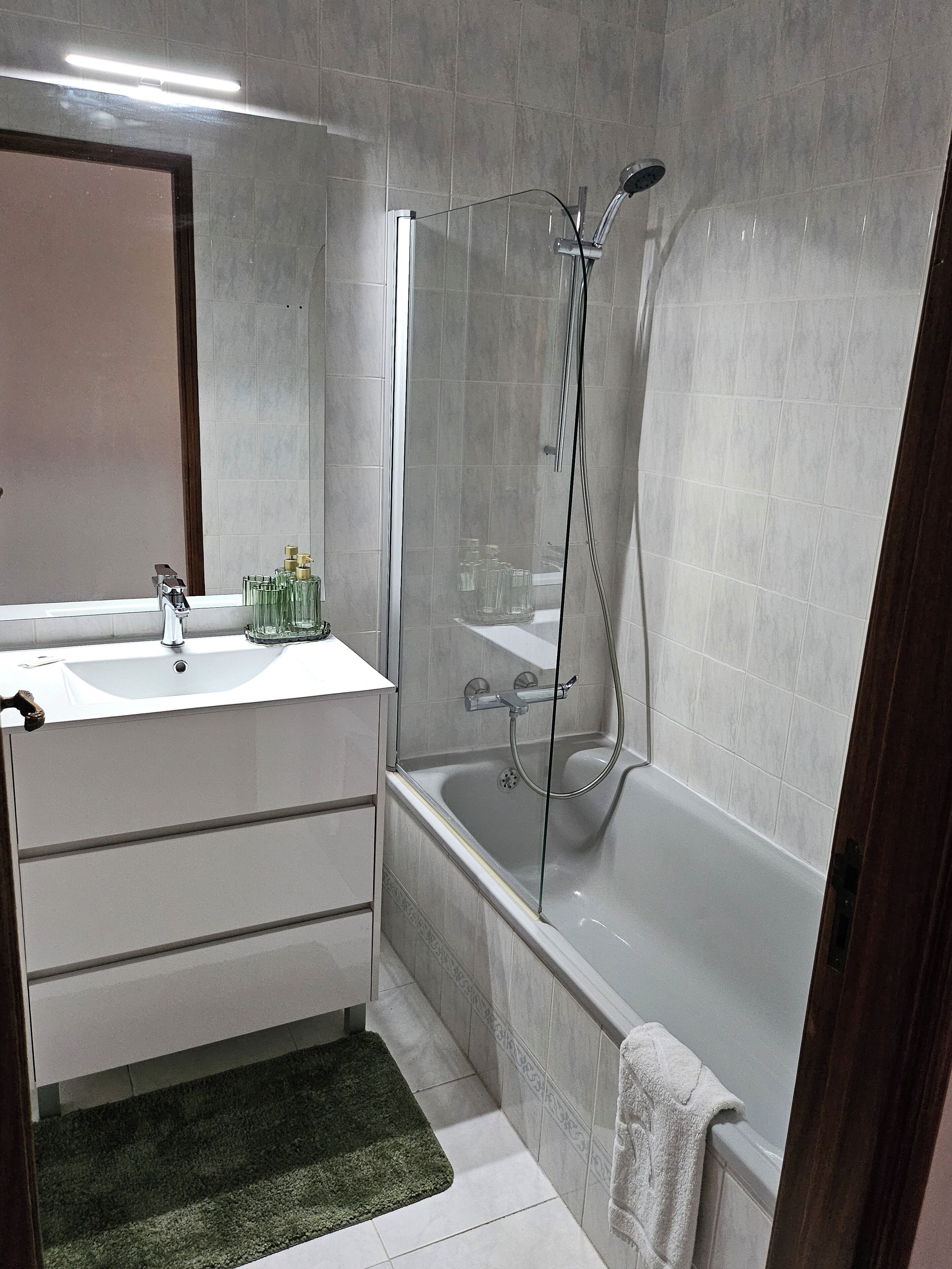 Un baño con ducha de vidrio, lavamanos blanco y espejo.