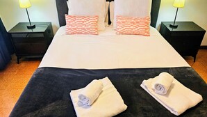 A neatly made bed with two pillows, two bedside tables with lamps, and two rolled towels on the bed. - Lucinda's House. Welcome (BRAGA)