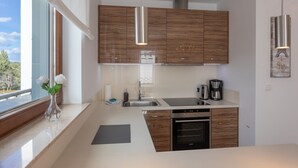 Une cuisine moderne avec des meubles en bois, des appareils électroménagers en acier inoxydable et une grande fenêtre offrant une vue sur l’extérieur.